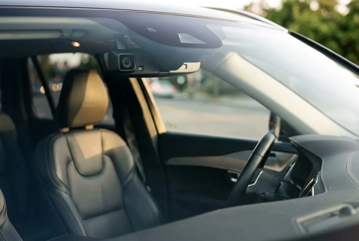 Small camera unit mounted high on a windshield, angled toward the driver seat.