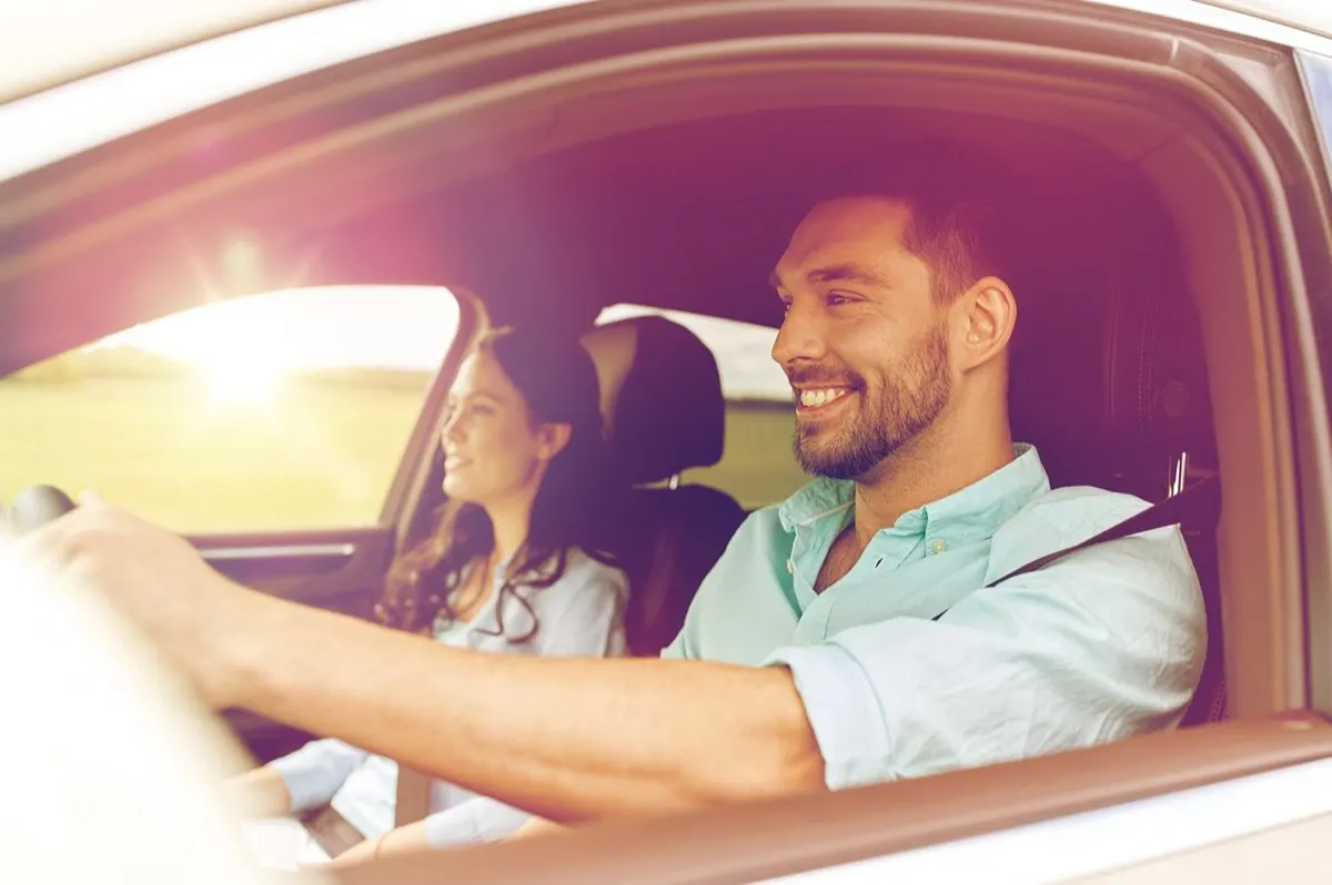Driver and passenger smiling on a daytime drive