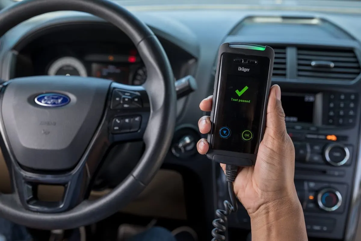 Driver holding an interlock handset that shows a passed breath test